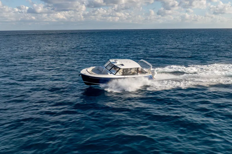 Slide: The Image of 2026 MJM 3 boat cruising on open ocean under a partly cloudy sky. - 2