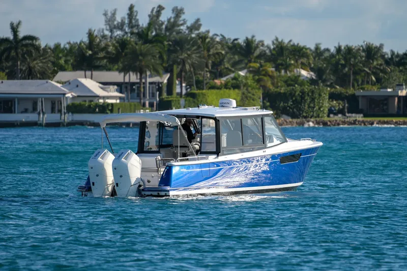 Slide: The Image of 2026 MJM 3 boat cruising on a sunny day near waterfront homes. - 23