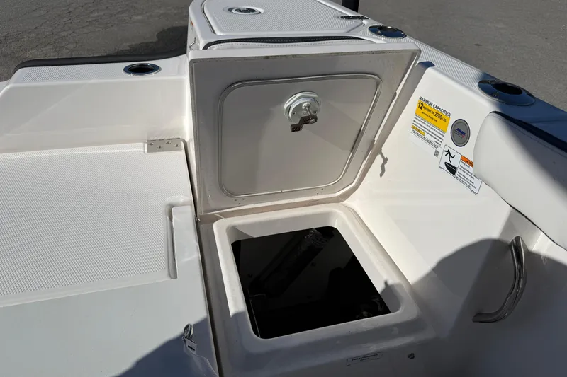 Slide: The Image of 2024 Yamaha Boats 255 FSH Sport H storage compartment with open hatch and capacity label. - 14