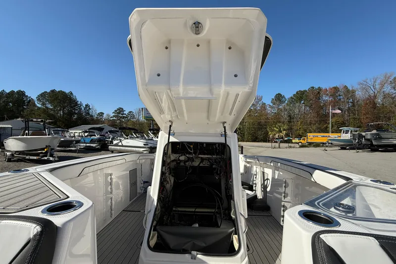 Slide: The Image of 2024 Yamaha Boats 255 FSH Sport H with open storage compartment, docked outdoors. - 15