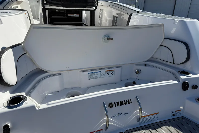 Slide: The Image of 2024 Yamaha Boats 255 FSH Sport H, open storage compartment, sleek white design. - 23
