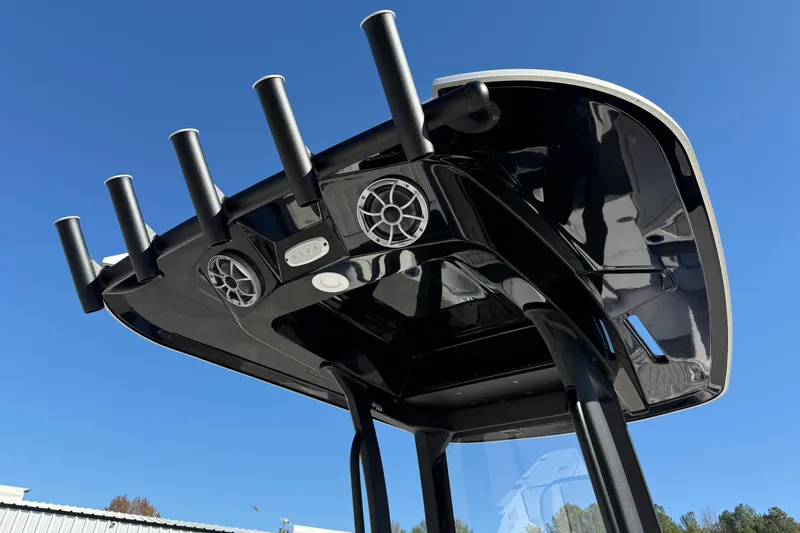 Slide: The Image of 2024 Yamaha Boats 255 FSH Sport H T-top with rod holders and speakers against blue sky. - 5