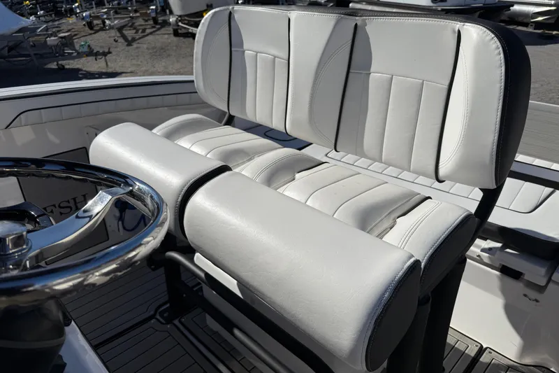 Slide: The Image of 2024 Yamaha Boats 255 FSH Sport H helm seat with steering wheel, featuring sleek white upholstery. - 6