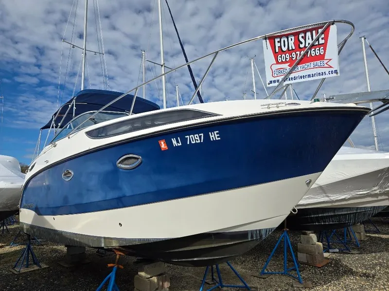 The Image of 2011 Bayliner 255 boat for sale, blue and white hull, displayed on stands. - 0