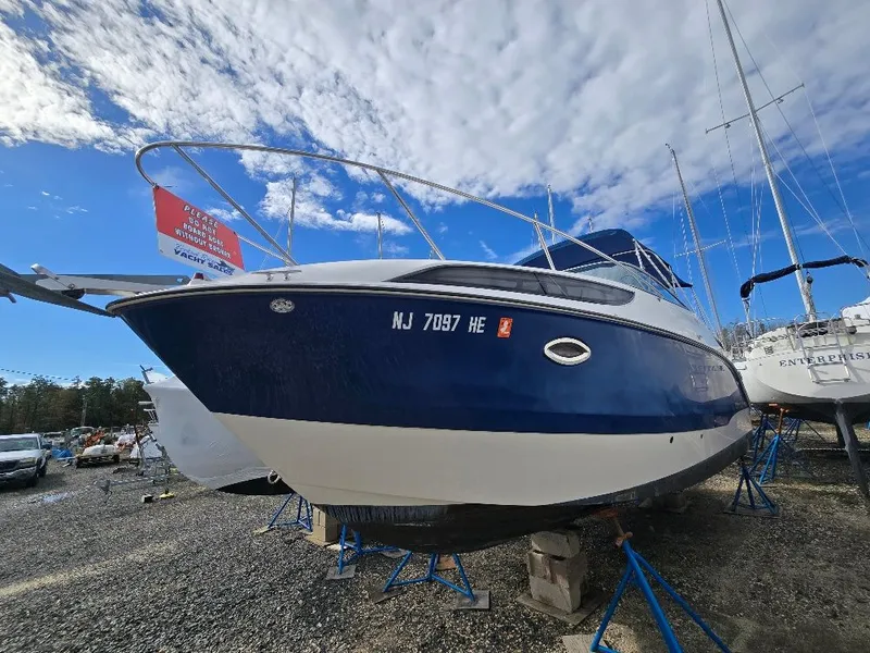 Slide: The Image of 2011 Bayliner 255 boat on stands, blue hull, clear sky background. - 1