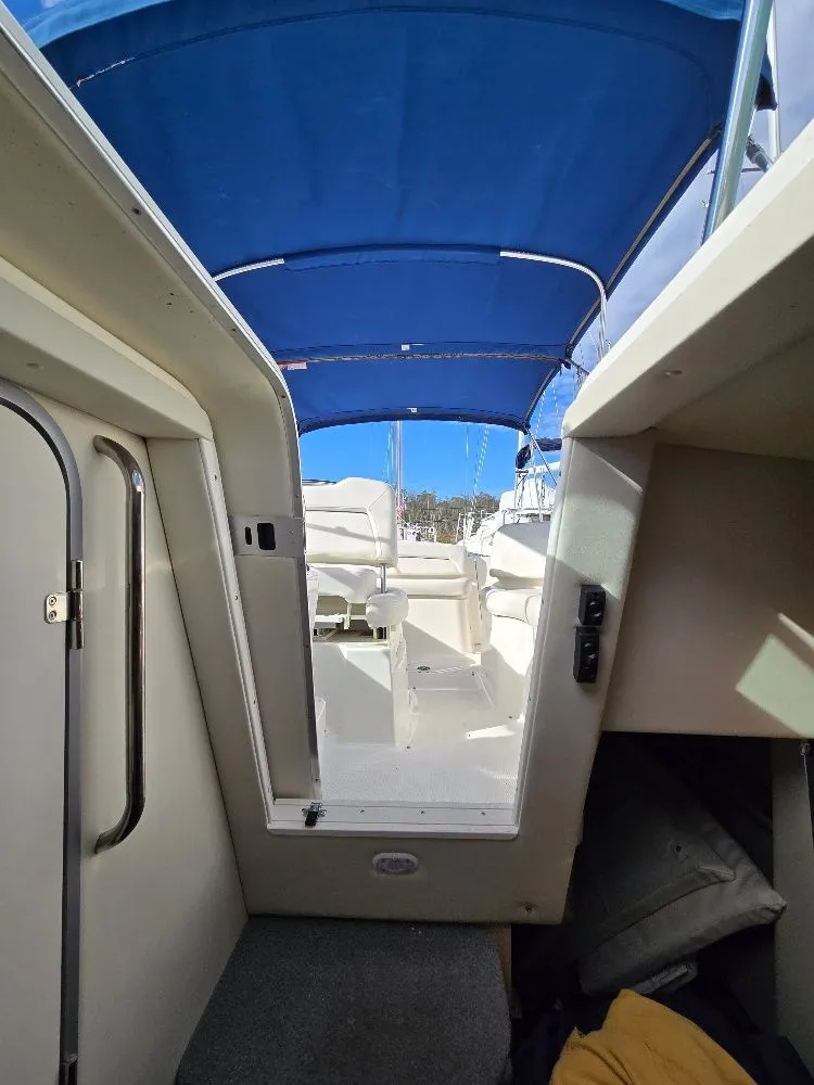 Slide: The Image of 2011 Bayliner 255 boat interior with blue canopy and white seating. - 17