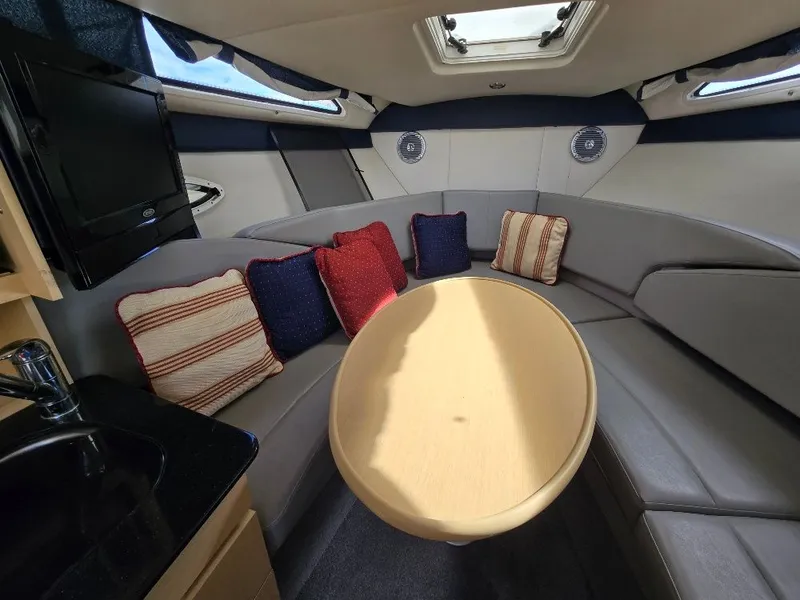 Slide: The Image of Interior of 2011 Bayliner 255 boat with cozy seating, cushions, and a round table. - 19