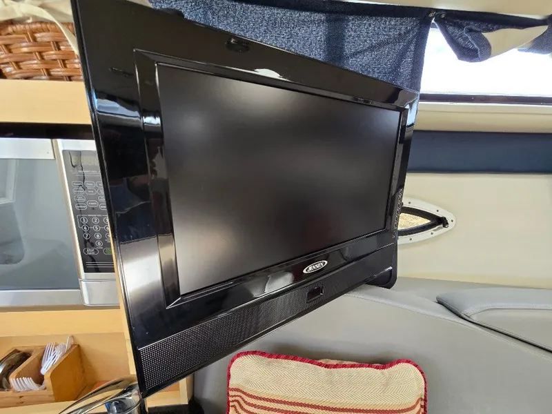 Slide: The Image of Flat-screen TV inside 2011 Bayliner 255 boat cabin, next to microwave and cushion. - 21