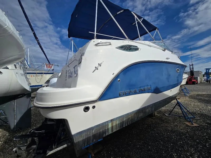 Slide: The Image of 2011 Bayliner 255 boat with blue and white exterior, docked under a clear sky. - 3