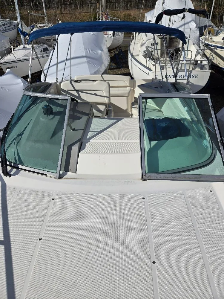 Slide: The Image of 2011 Bayliner 255 boat with open windshield and blue canopy, docked among other boats. - 6