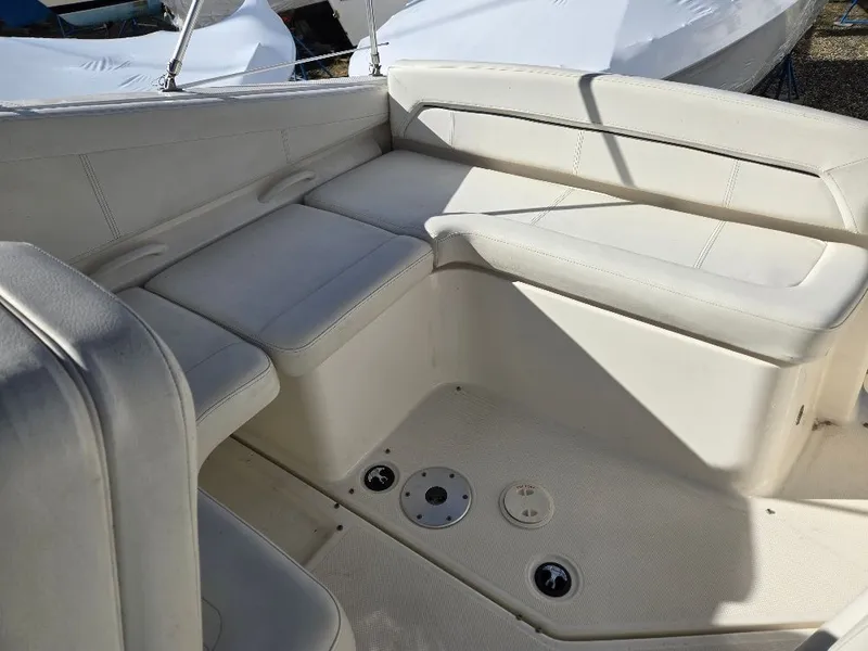 Slide: The Image of 2011 Bayliner 255 boat interior with white cushioned seating and deck details. - 7