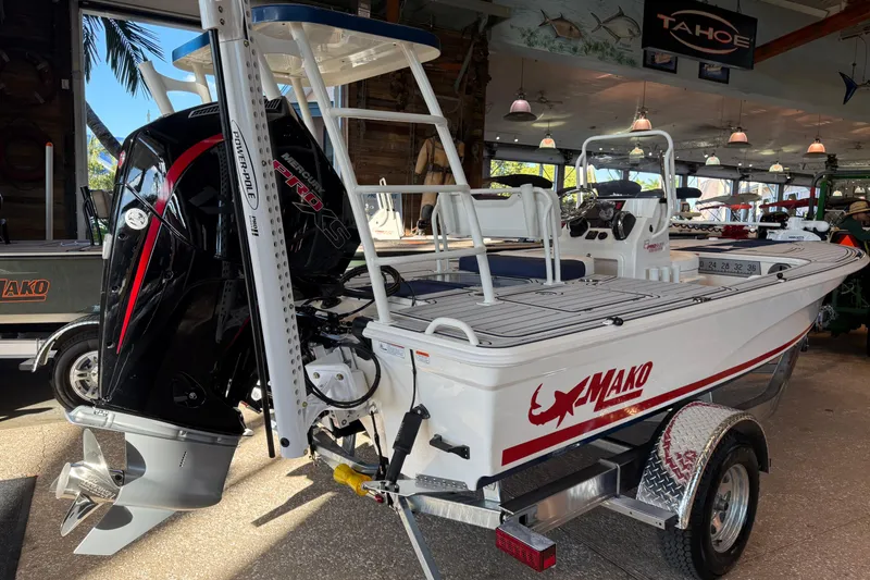 Slide: The Image of 2026 Mako 18 Pro Skiff Patriot Edition boat displayed indoors with powerful outboard motor. - 2