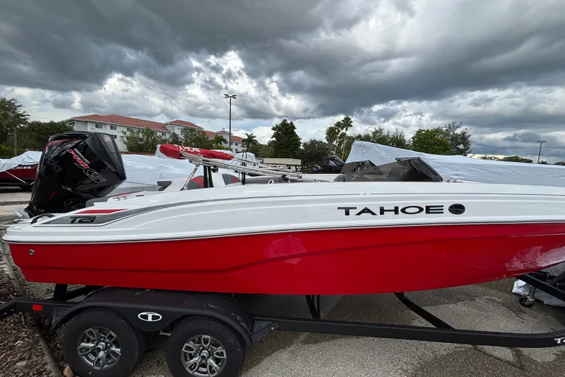 The Image of 2026 Tahoe T21 boat in red and white on trailer under cloudy sky. - 0