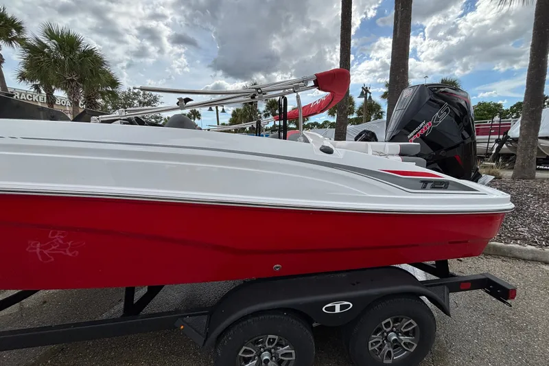 Slide: The Image of 2026 Tahoe T21 boat with red and white design on a trailer, parked outdoors. - 3