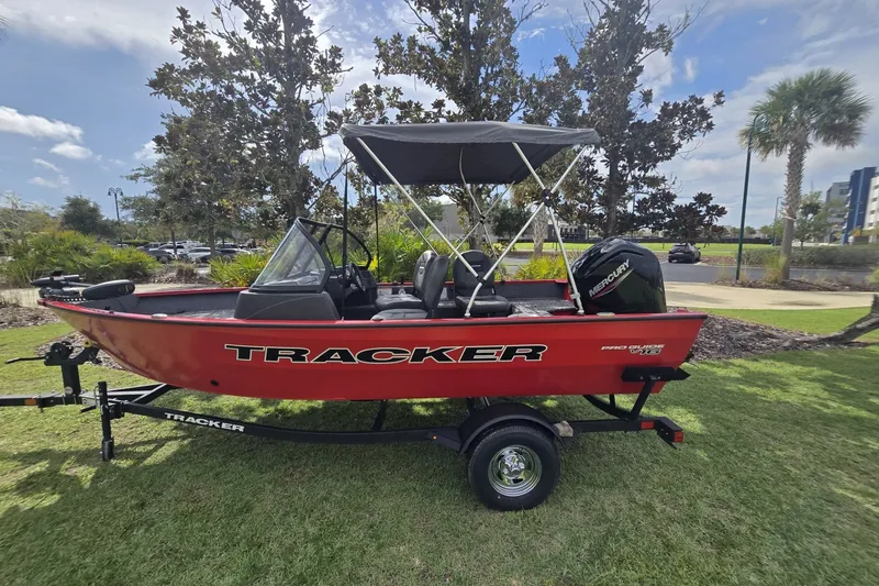 The Image of 2026 Tracker Pro Guide V-16 WT boat on trailer, parked on grass under a sunny sky. - 0