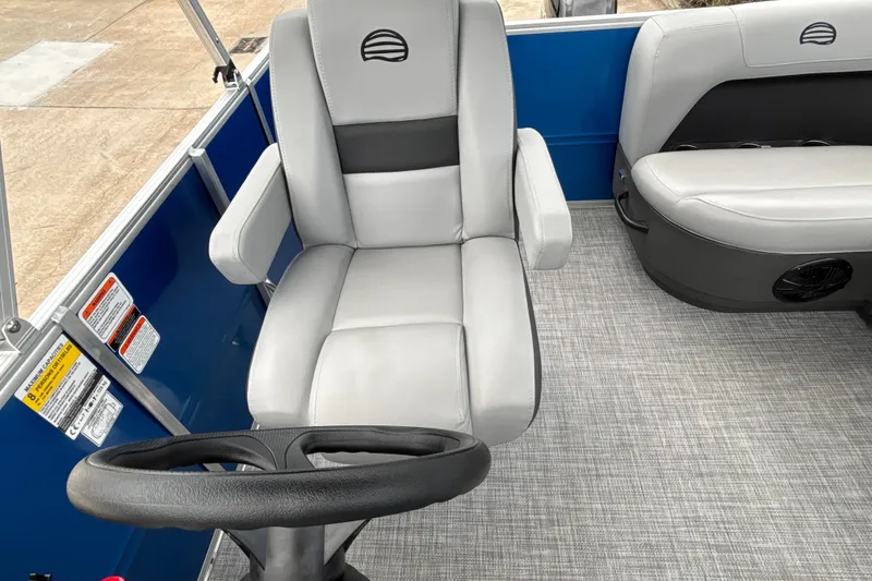 Slide: The Image of 2026 Sun Tracker Party Barge 16 DLX interior with gray seating and steering wheel. - 14