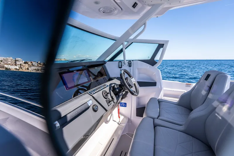 Slide: The Image of 2026 Axopar 29 Sun Top boat interior with modern dashboard and ocean view. - 11