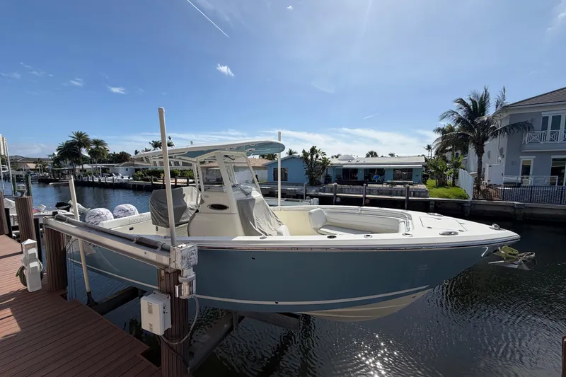 The Image of 2021 Cobia 262 Center Console boat docked by waterfront homes under clear sky. - 0