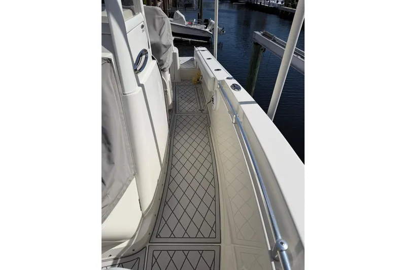Slide: The Image of 2021 Cobia 262 Center Console boat deck with diamond-pattern flooring, docked by the water. - 18
