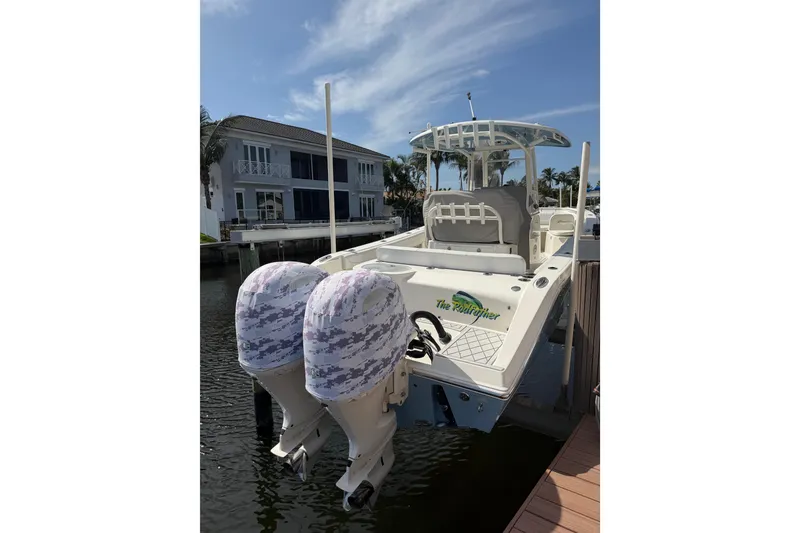 Slide: The Image of 2021 Cobia 262 Center Console boat docked, featuring dual engines and a spacious deck. - 2