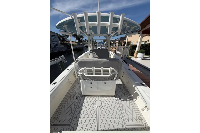 Slide: The Image of 2021 Cobia 262 Center Console boat interior with rod holders and seating, docked by waterfront homes. - 27