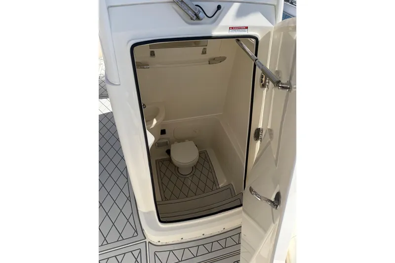 Slide: The Image of 2021 Cobia 262 Center Console boat interior with open door revealing compact bathroom. - 28