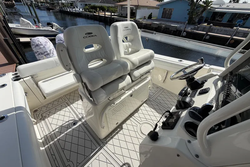 Slide: The Image of 2021 Cobia 262 Center Console boat interior with helm and seating, docked by waterfront. - 8