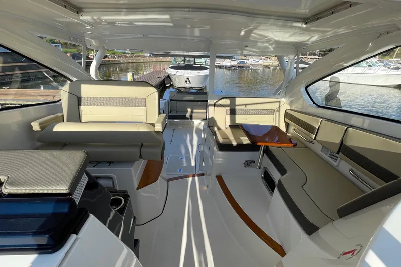 Slide: The Image of 2020 Pursuit DC 365 Dual Console boat interior with seating and table, docked at marina. - 14
