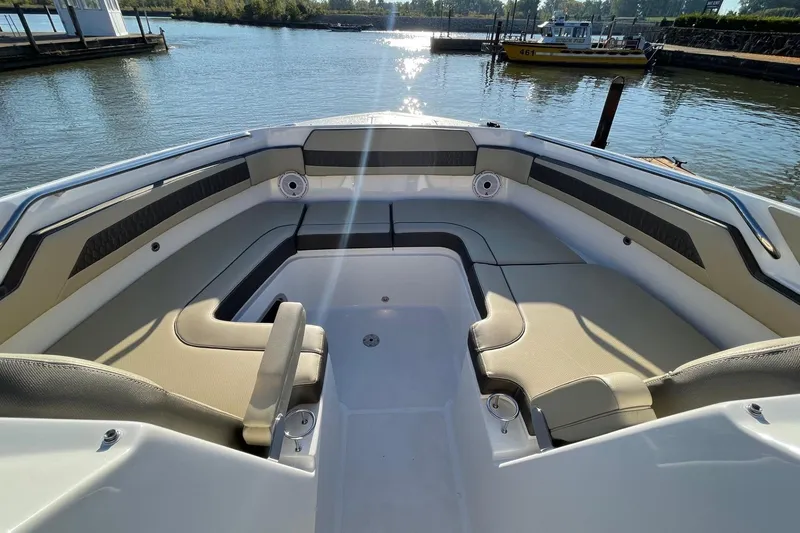 Slide: The Image of 2020 Pursuit DC 365 Dual Console boat interior with spacious seating, docked by calm waters. - 15