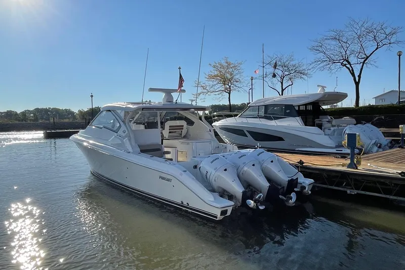 Slide: The Image of 2020 Pursuit DC 365 Dual Console boat docked in sunny marina setting. - 2