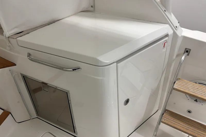 Slide: The Image of 2020 Pursuit DC 365 Dual Console boat interior with storage compartment and wooden steps. - 26