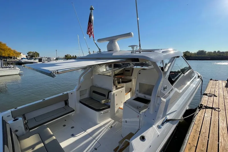 Slide: The Image of 2020 Pursuit DC 365 Dual Console boat docked, featuring spacious seating and an extended canopy. - 3