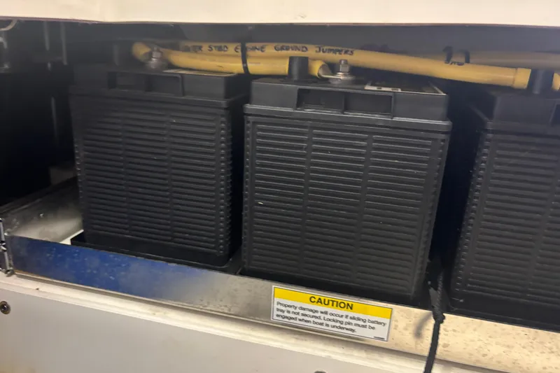 Slide: The Image of Battery compartment of a 2020 Pursuit DC 365 Dual Console boat with caution label. - 47