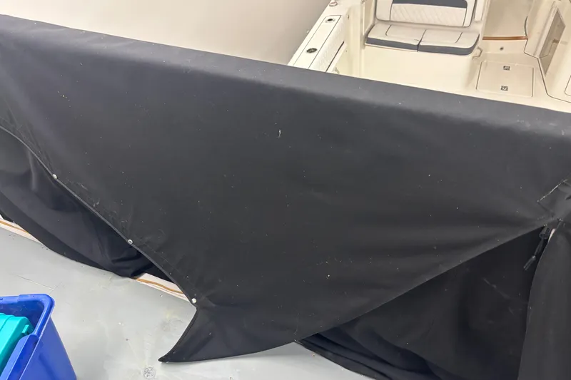 Slide: The Image of 2020 Pursuit DC 365 Dual Console boat partially covered with black tarp in storage. - 56