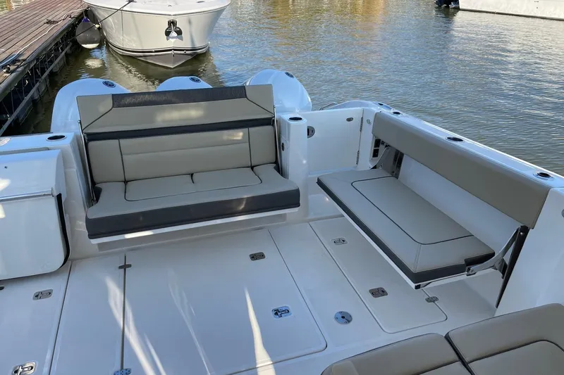 Slide: The Image of 2020 Pursuit DC 365 Dual Console boat interior with cushioned seating, docked on calm water. - 8