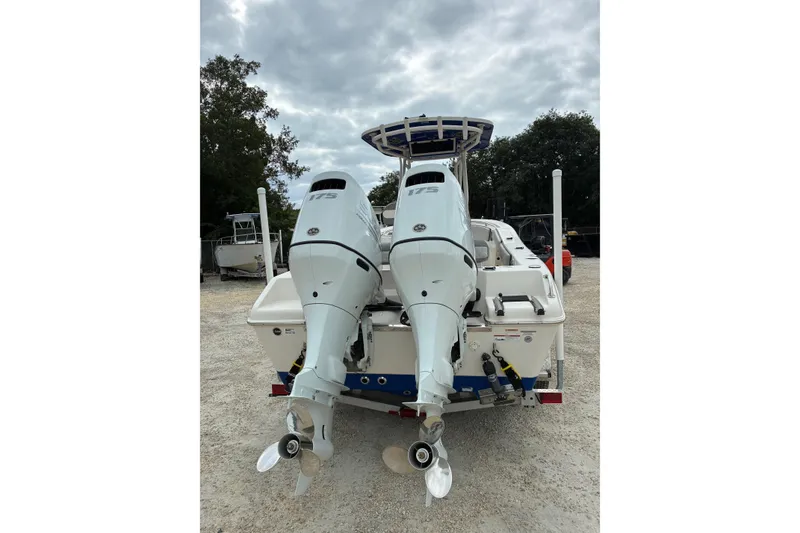 Slide: The Image of 2023 Sea Chaser 24 HFC boat with dual outboard motors, parked on gravel. - 2