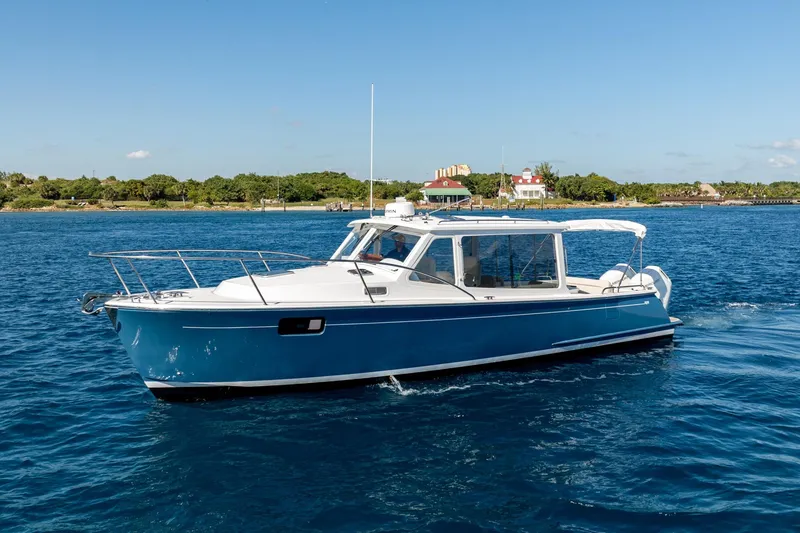 Slide: The Image of 2025 MJM 35 boat cruising on blue water near a scenic shoreline. - 13