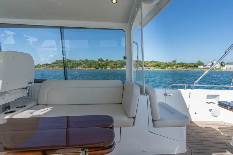 Slide: The Image of 2025 MJM 35 yacht interior with white seating, wooden table, and ocean view. - 25