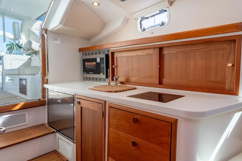 Slide: The Image of Modern MJM 35 yacht interior kitchen with wood cabinetry, induction cooktop, and microwave, 2025 model. - 31