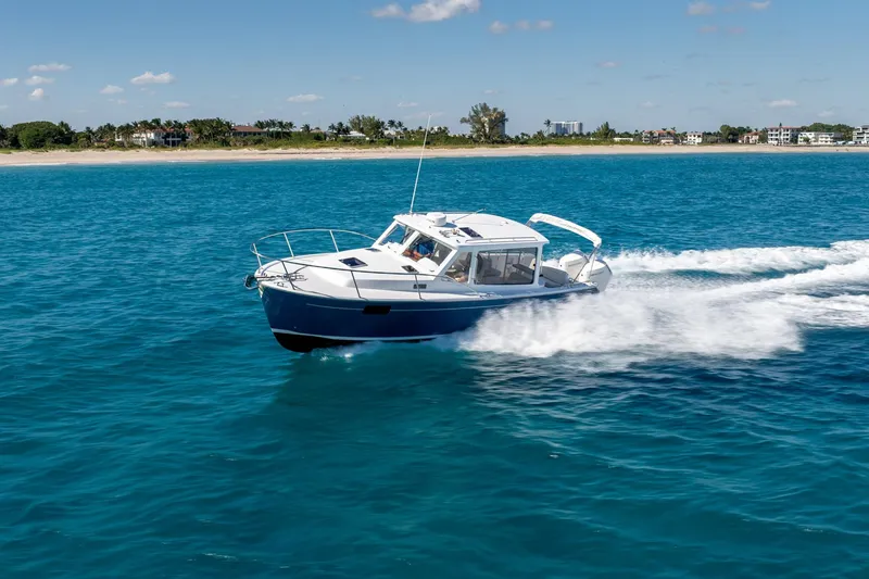 Slide: The Image of 2025 MJM 35 boat cruising on clear blue ocean near a sandy coastline. - 8