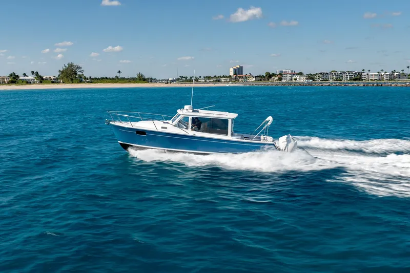 Slide: The Image of 2025 MJM 35 boat cruising on clear blue ocean near a coastal city. - 9