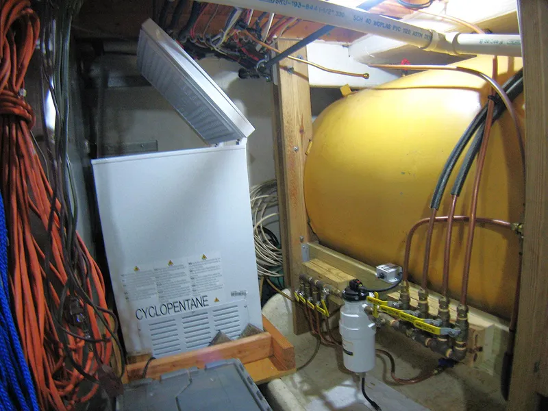 Slide: The Image of A 1987 Custom Pilgrim Tribute engine room with a yellow tank and various cables. - 49