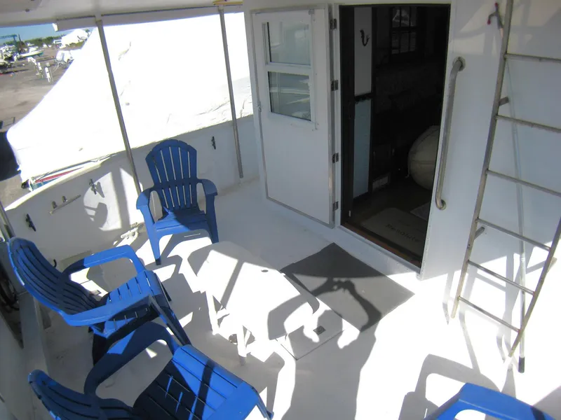 Slide: The Image of Deck of 1987 Custom Pilgrim Tribute boat with blue chairs and open cabin door. - 5