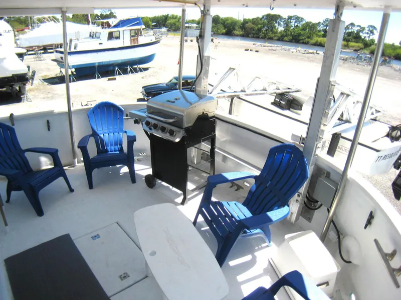 Slide: The Image of Outdoor deck of 1987 Custom Pilgrim Tribute boat with blue chairs and a grill. - 6
