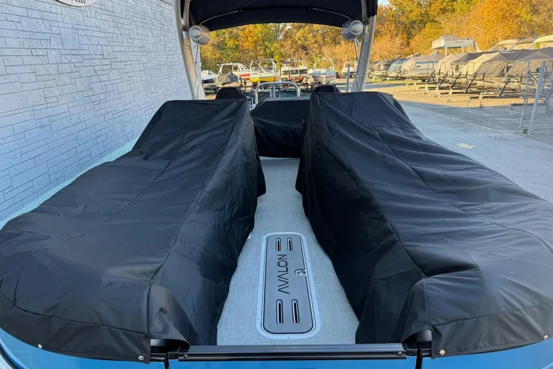 Slide: The Image of 2026 Avalon 2585 Excalibur LTD Flex Windshield boat with black covers, docked outdoors. - 24