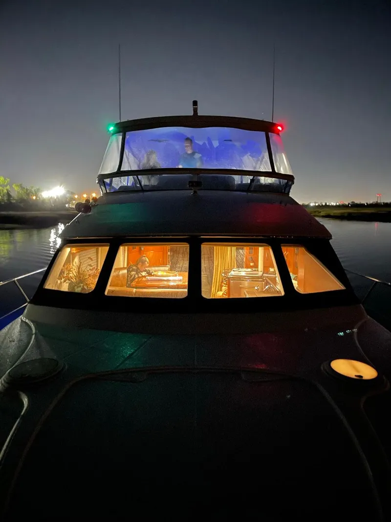 Slide: The Image of 2009 Silverton 52 Ovation yacht illuminated at night, showcasing interior and navigation lights. - 24
