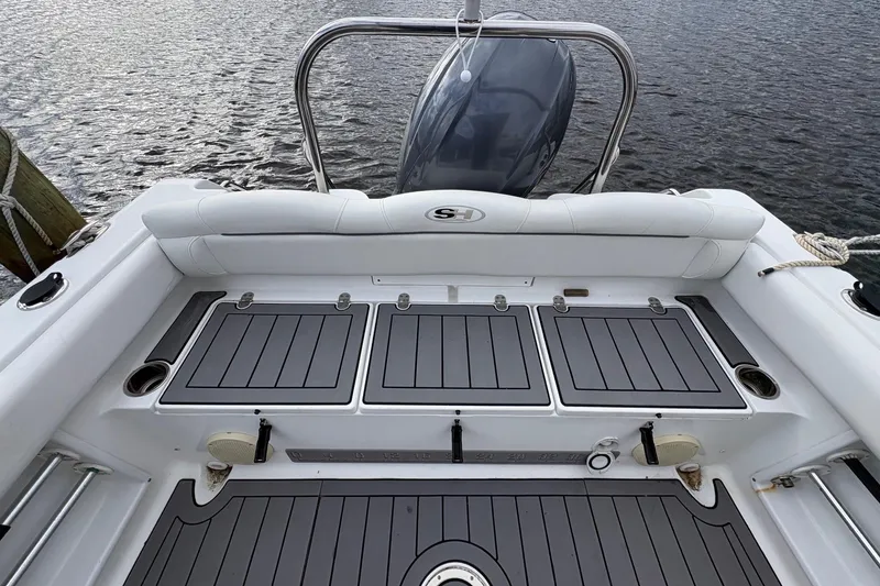 Slide: The Image of 2015 Sea Hunt Ultra 234 boat deck with storage compartments and motor, docked on water. - 8