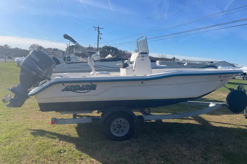 The Image of 2010 Sundance NX19 boat on trailer with Yamaha outboard motor, parked on grass. - 0