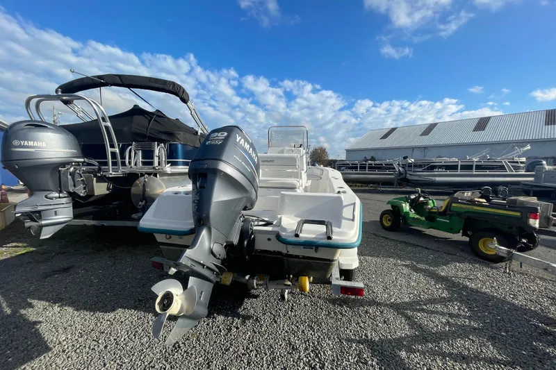 Slide: The Image of 2010 Sundance NX19 boat with Yamaha outboard motor, parked near other boats and a utility vehicle. - 11