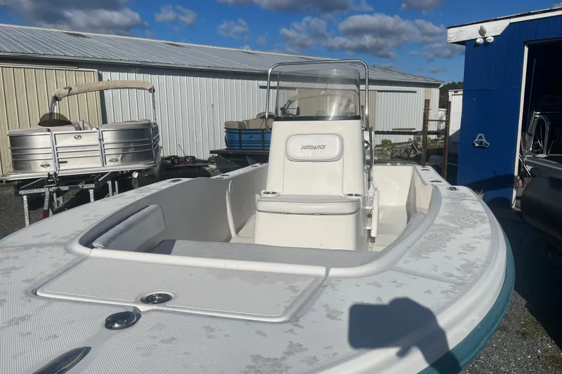 Slide: The Image of 2010 Sundance NX19 boat with center console, parked outdoors under a blue sky. - 2